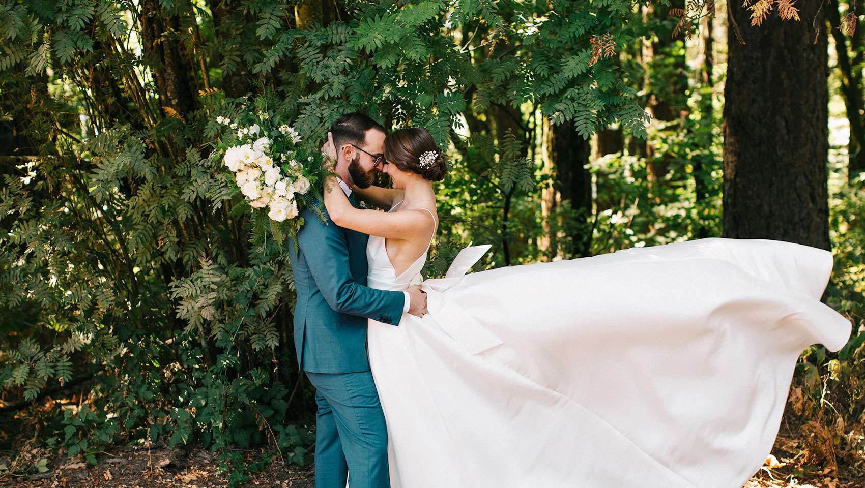 wedding couple hugging in front of trees